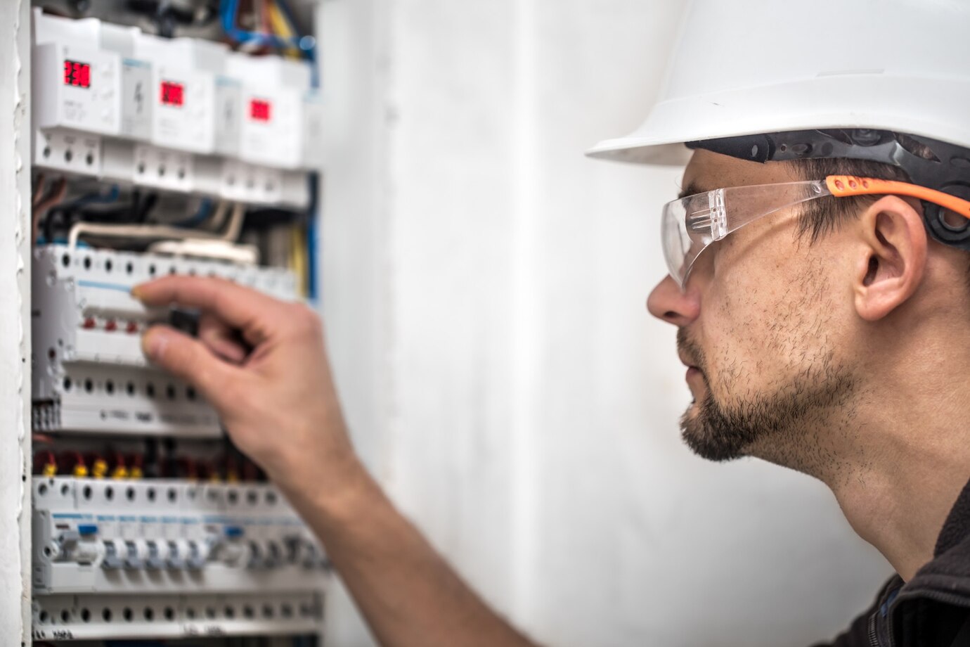 Electrical technician working on a switchboard with fuses, installing and connecting electrical equipment.